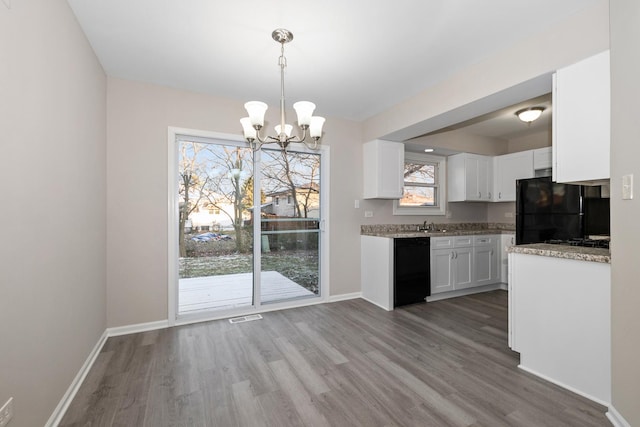 kitchen with a healthy amount of sunlight, black appliances, white cabinets, a chandelier, and hanging light fixtures