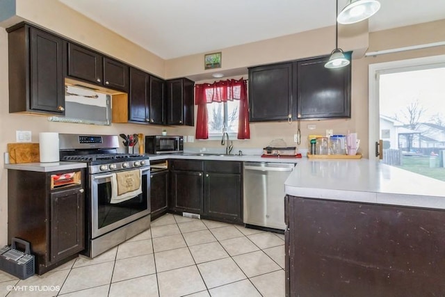 kitchen featuring sink, decorative light fixtures, dark brown cabinets, light tile patterned floors, and stainless steel appliances