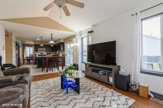 living room featuring hardwood / wood-style flooring, ceiling fan, and vaulted ceiling