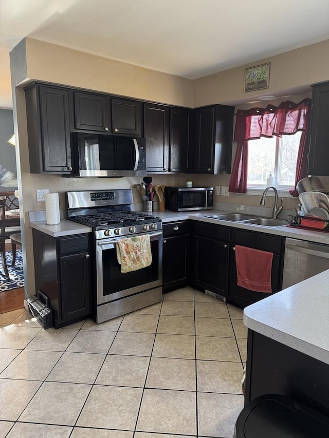 kitchen with appliances with stainless steel finishes, sink, and light tile patterned floors