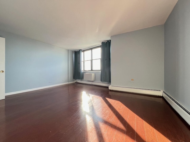 empty room featuring hardwood / wood-style flooring and baseboard heating