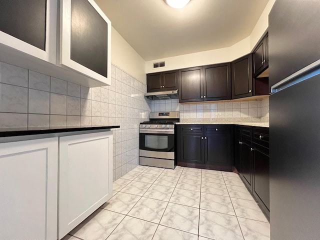 kitchen featuring stainless steel range, decorative backsplash, light stone counters, and dark brown cabinets