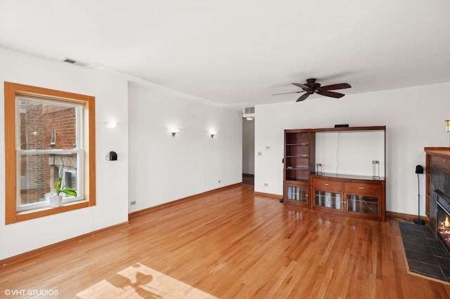 unfurnished living room featuring hardwood / wood-style floors, a tile fireplace, and ceiling fan