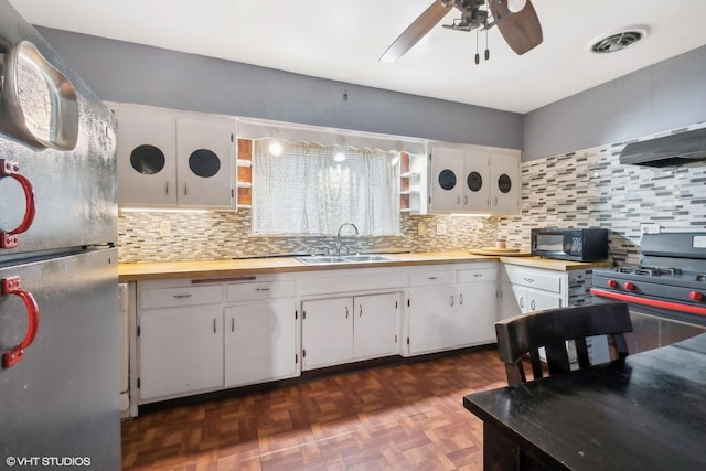 kitchen featuring sink, appliances with stainless steel finishes, dark parquet flooring, white cabinets, and decorative backsplash