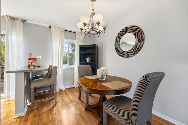 dining space featuring light wood-type flooring and an inviting chandelier