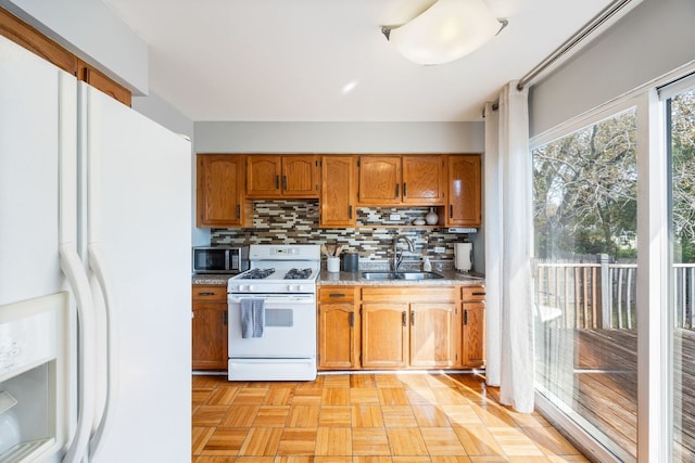 kitchen featuring backsplash, sink, light parquet flooring, and white appliances