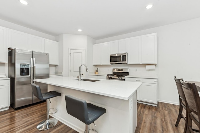 kitchen with a kitchen bar, appliances with stainless steel finishes, a kitchen island with sink, sink, and white cabinets