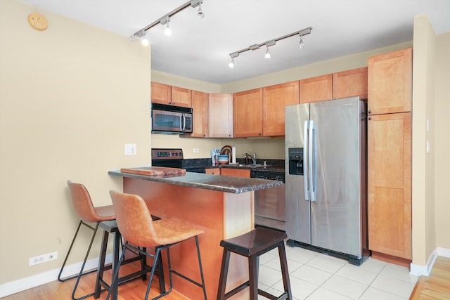 kitchen featuring sink, stainless steel appliances, a kitchen breakfast bar, kitchen peninsula, and light tile patterned floors