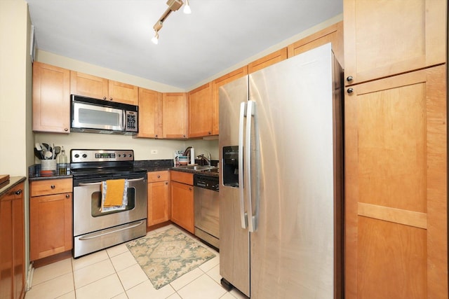 kitchen with sink, stainless steel appliances, rail lighting, and light tile patterned flooring