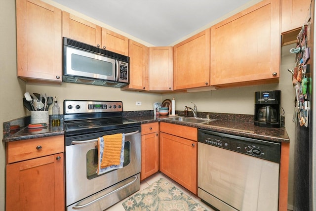 kitchen with stainless steel appliances, dark stone counters, and sink