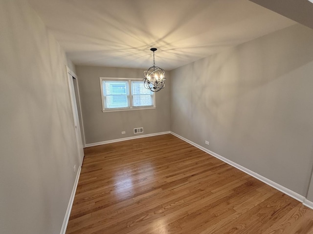 spare room featuring hardwood / wood-style floors and a notable chandelier