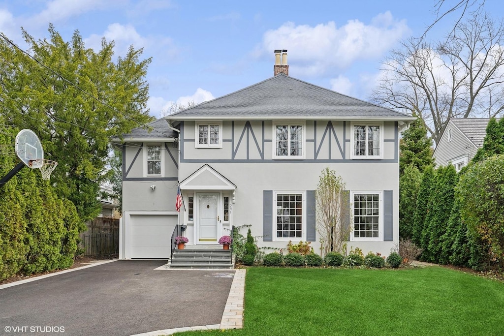 tudor home featuring a front yard and a garage