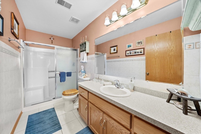 bathroom featuring walk in shower, tile patterned flooring, toilet, vanity, and tile walls