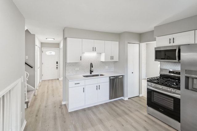 kitchen featuring sink, white cabinets, light hardwood / wood-style floors, and appliances with stainless steel finishes