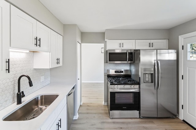 kitchen with decorative backsplash, white cabinetry, sink, and stainless steel appliances