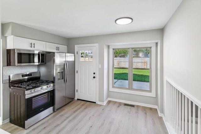 kitchen with white cabinetry, stainless steel appliances, and light hardwood / wood-style flooring