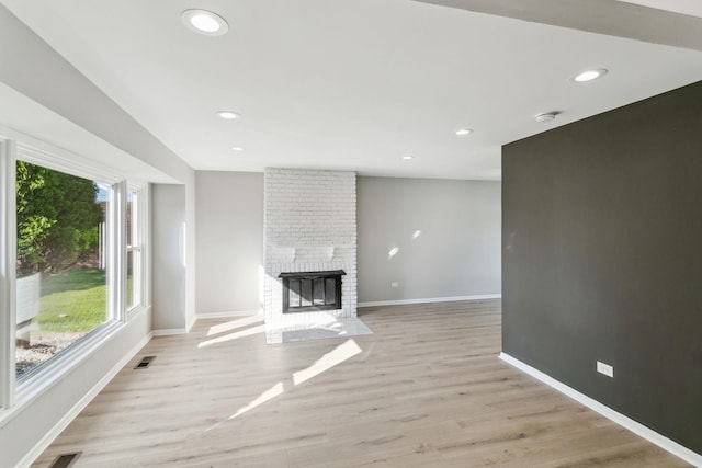 unfurnished living room featuring a fireplace and light hardwood / wood-style floors