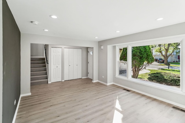 unfurnished bedroom featuring light hardwood / wood-style floors and two closets