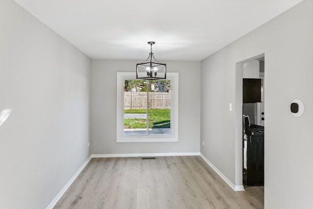 unfurnished dining area featuring light hardwood / wood-style flooring and a notable chandelier