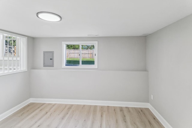 empty room featuring a wealth of natural light, electric panel, and light wood-type flooring