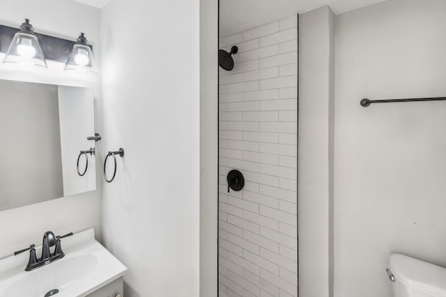 bathroom with vanity, toilet, and tiled shower