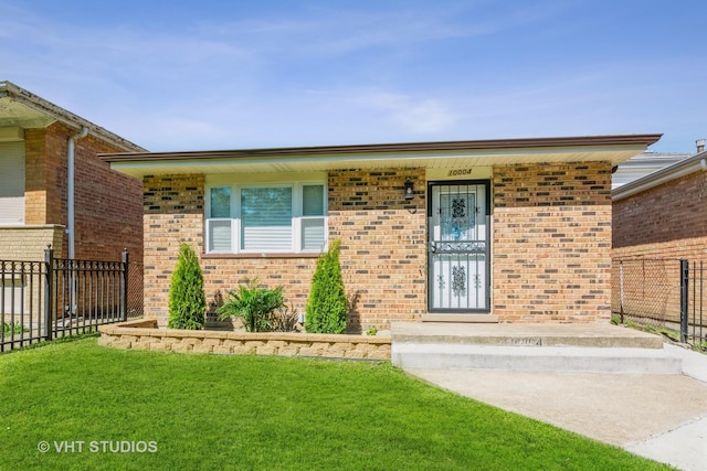 view of exterior entry with fence, brick siding, and a lawn