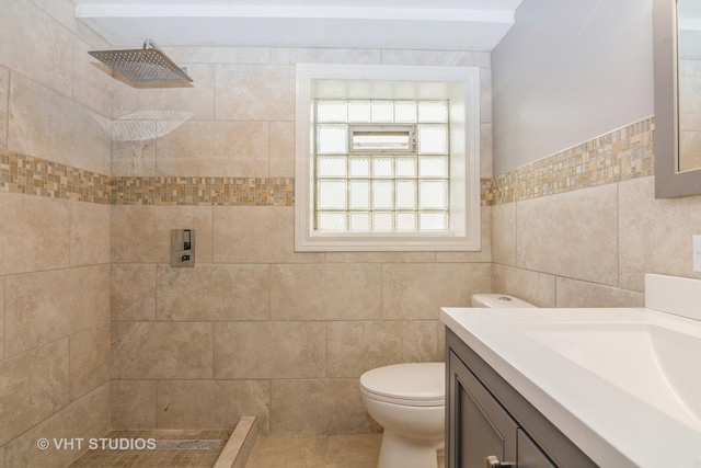 full bathroom with vanity, tile walls, toilet, and a tile shower