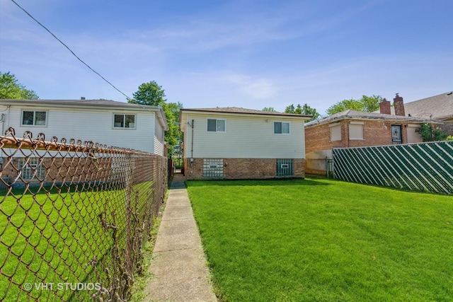 rear view of house with a lawn and a fenced backyard