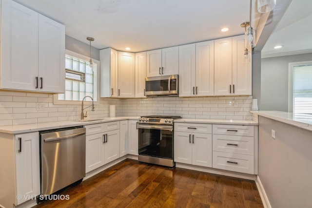 kitchen featuring dark wood-type flooring, decorative backsplash, stainless steel appliances, white cabinetry, and a sink