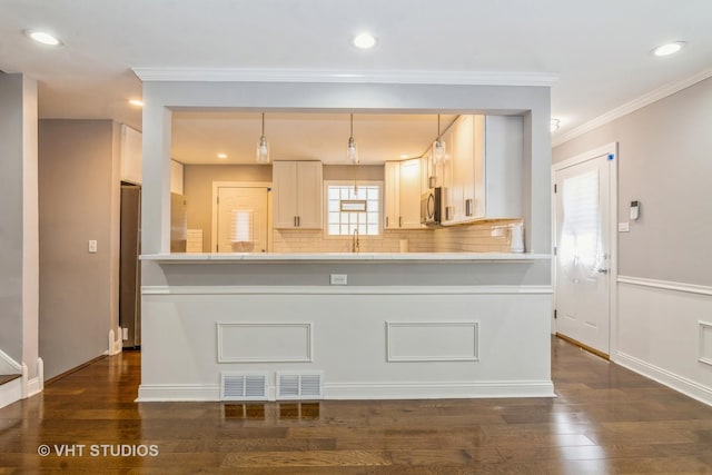 kitchen with stainless steel microwave, dark wood-type flooring, a peninsula, and light countertops