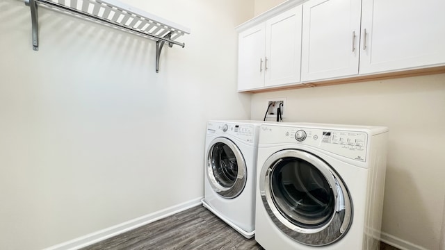 clothes washing area featuring cabinets, washer and dryer, and dark wood-type flooring