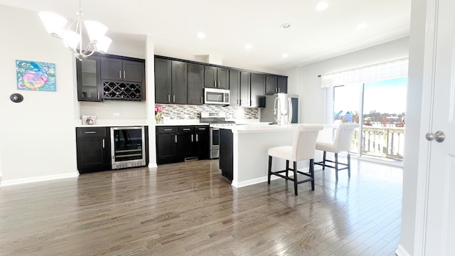 kitchen featuring backsplash, hanging light fixtures, light hardwood / wood-style floors, stainless steel appliances, and beverage cooler