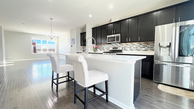 kitchen with a center island with sink, stainless steel appliances, decorative light fixtures, and an inviting chandelier