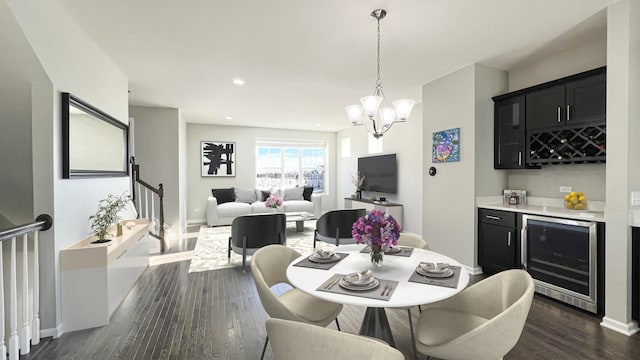 dining area with dark hardwood / wood-style floors, a chandelier, beverage cooler, and indoor bar