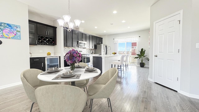 dining room with a chandelier, beverage cooler, and light hardwood / wood-style flooring