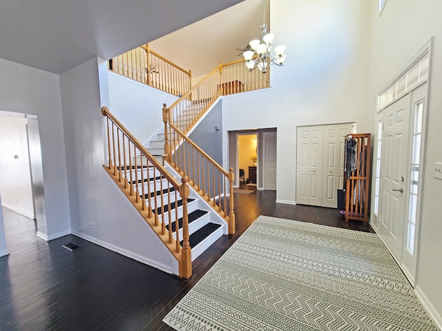 entryway with dark wood-type flooring, a chandelier, and a high ceiling