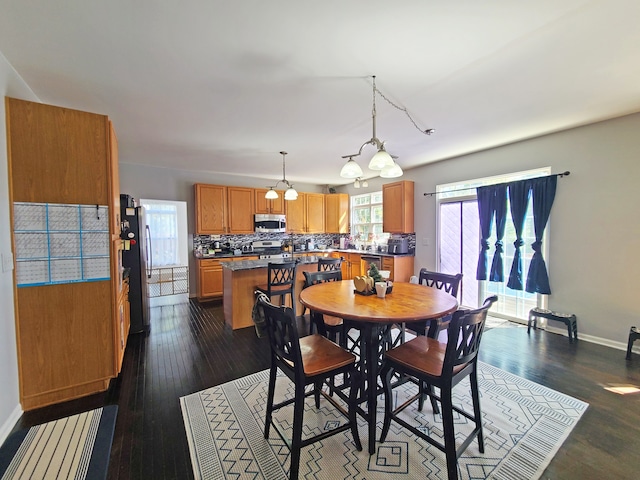 dining area with dark wood-type flooring and an inviting chandelier