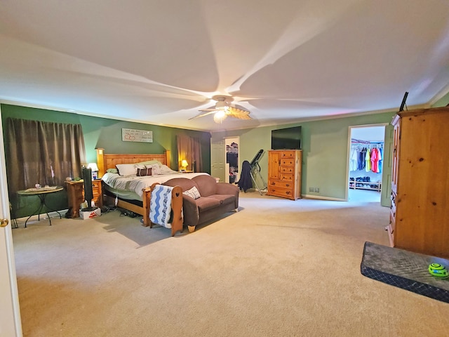 bedroom featuring ceiling fan, a walk in closet, light carpet, and a closet