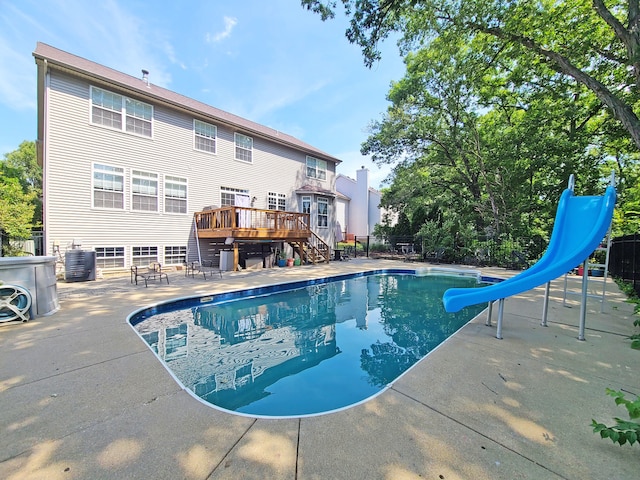 view of pool featuring a patio, a deck, cooling unit, and a water slide