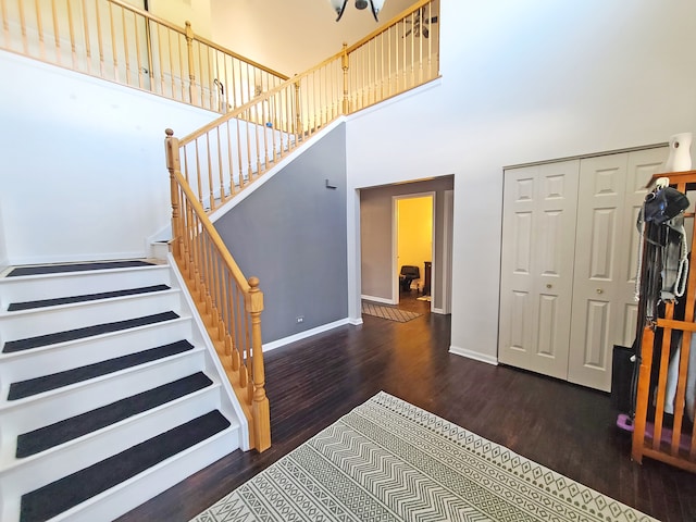 stairway with wood-type flooring and a high ceiling