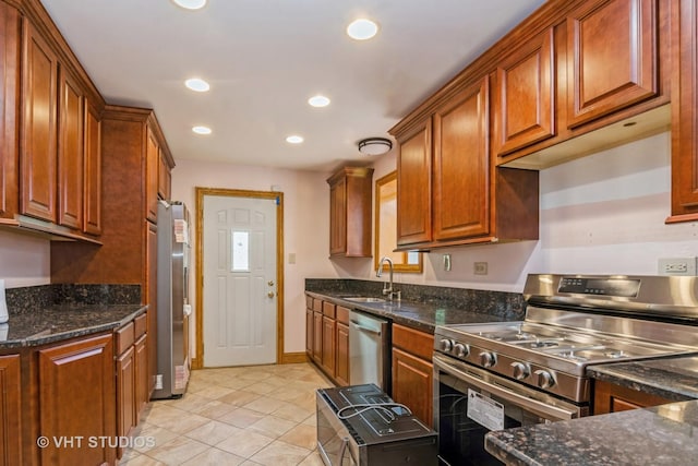 kitchen featuring dark stone counters, recessed lighting, brown cabinets, appliances with stainless steel finishes, and a sink