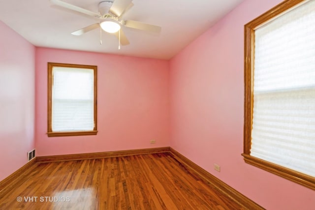 spare room with visible vents, wood finished floors, baseboards, and ceiling fan