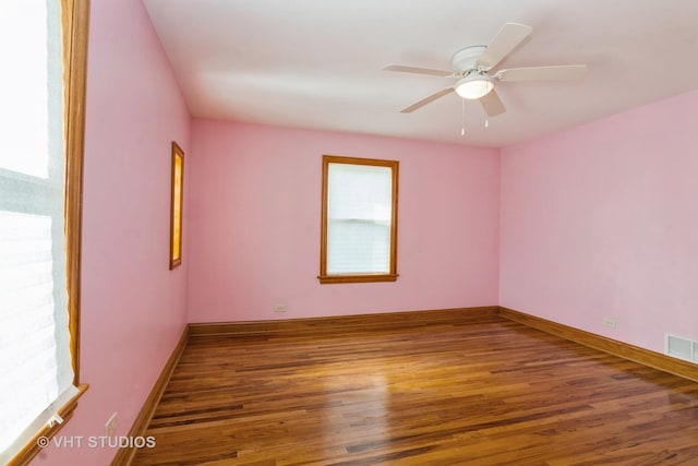 spare room with visible vents, a ceiling fan, baseboards, and wood finished floors