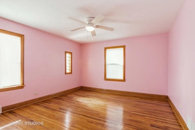 empty room with ceiling fan, visible vents, baseboards, and wood finished floors