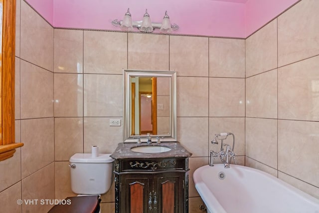 full bathroom featuring vanity, tile walls, a freestanding tub, and toilet