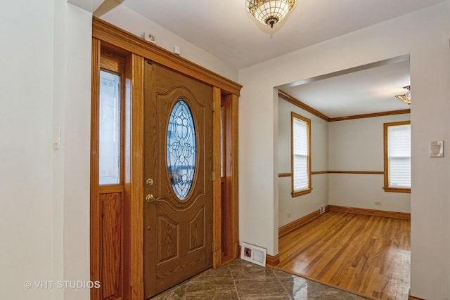 entrance foyer with visible vents, wood finished floors, baseboards, and ornamental molding