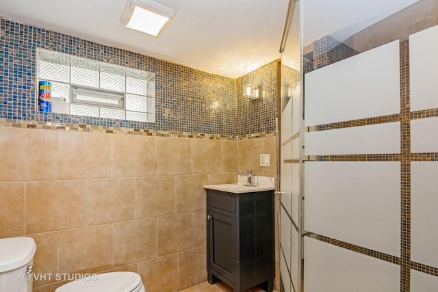 full bath featuring toilet, tile walls, vanity, and a tile shower