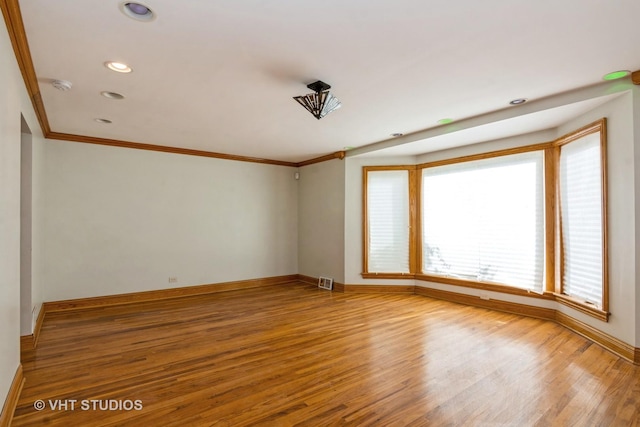 empty room with visible vents, baseboards, ornamental molding, recessed lighting, and wood finished floors