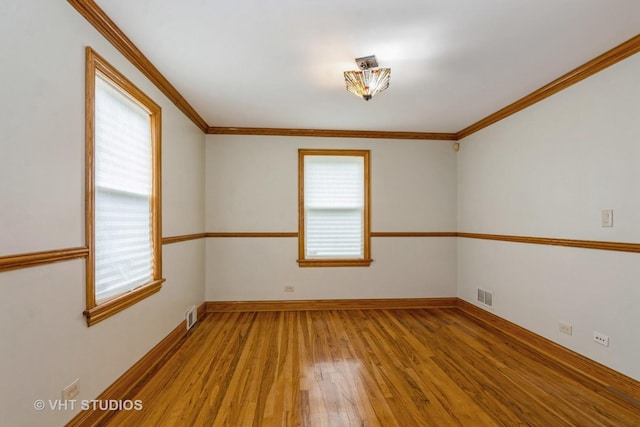 unfurnished room with light wood finished floors, visible vents, and crown molding