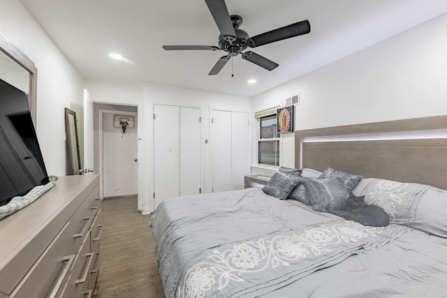 bedroom with ceiling fan, wood-type flooring, and two closets